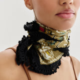 Woman wearing a floral bandana with black lace around her neck against a white background