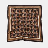 A square patterned scarf with a geometric interlocking circle design in brown, beige, and black, finished with a wide brown border, laid flat on a light gray background.