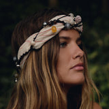 Woman with long hair wearing a decorative headband against a blurred natural background