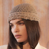 Woman wearing a beige knitted hat against a neutral background
