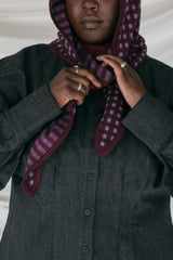 Person wearing a dark coat and a patterned scarf against a neutral background