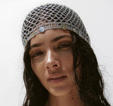 Woman wearing a silver fishnet headband against a white background