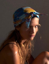 Woman with a colorful headscarf sitting against a plain background