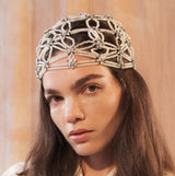 Woman wearing a decorative headpiece against a neutral background