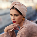 Woman wearing a beige headscarf and coat with a blurred background