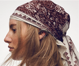 Woman wearing a patterned headscarf with long blonde hair on a white background