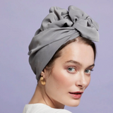 Woman wearing a gray headscarf against a light purple background