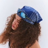 Person wearing a blue bandana with sunglasses on top, against a white background