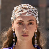 Close-up of a woman wearing a decorative headpiece with pearls and beads.