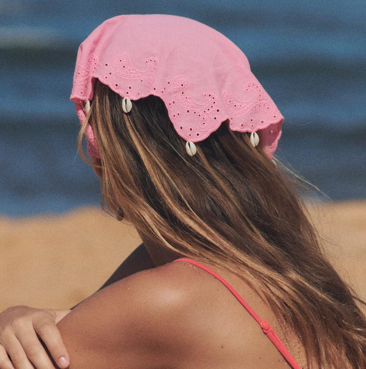 Woman in a pink bikini sitting on a beach with ocean in the background