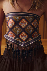 Decorative waistband with intricate patterns and fringes on a person wearing a dark dress.