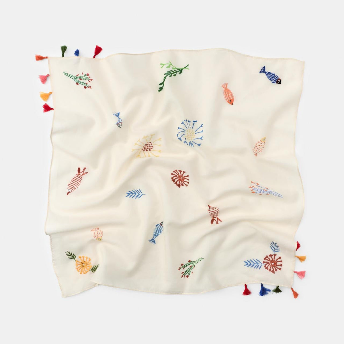 Embroidered blanket with colorful designs and tassels on a white background