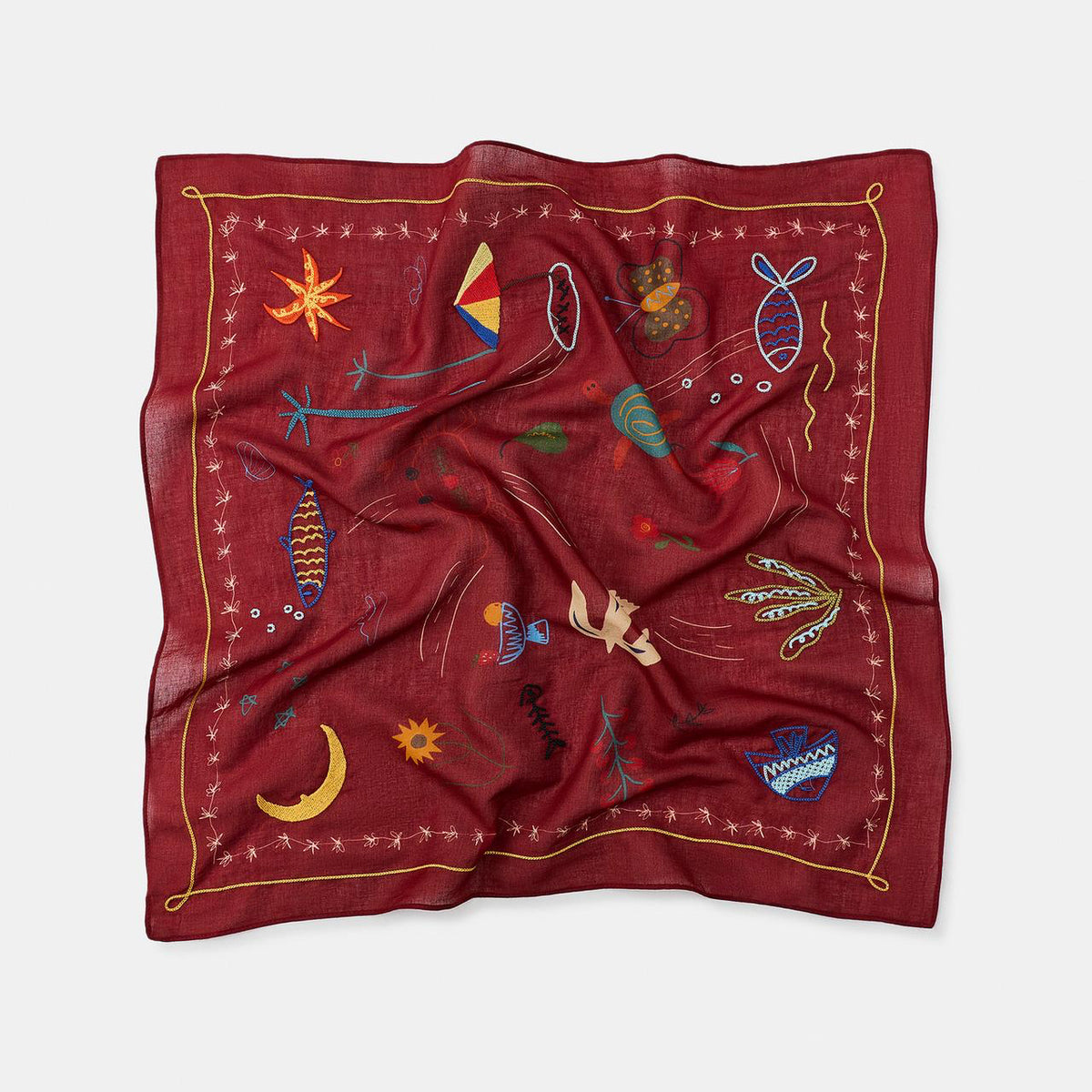 Red scarf with embroidered designs on a white background