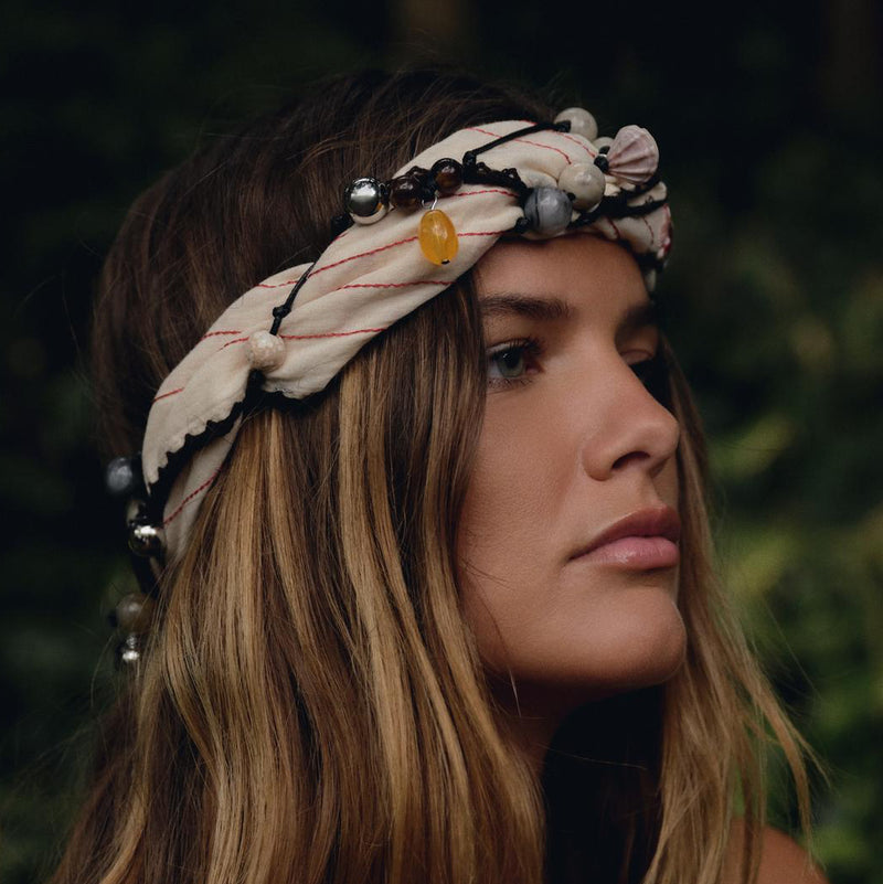 Woman with long hair wearing a decorative headband against a blurred natural background