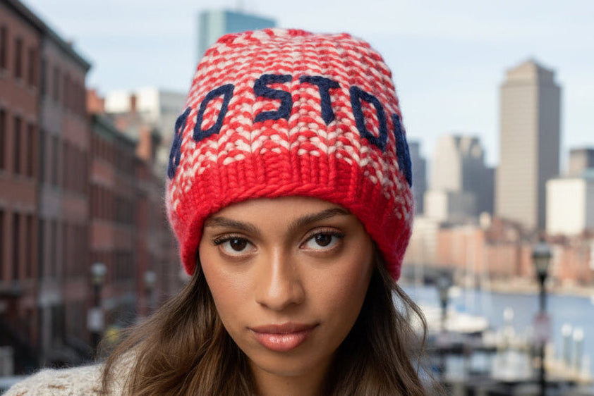 Person wearing a red and white knit beanie with 'Boston' text on a yellow background