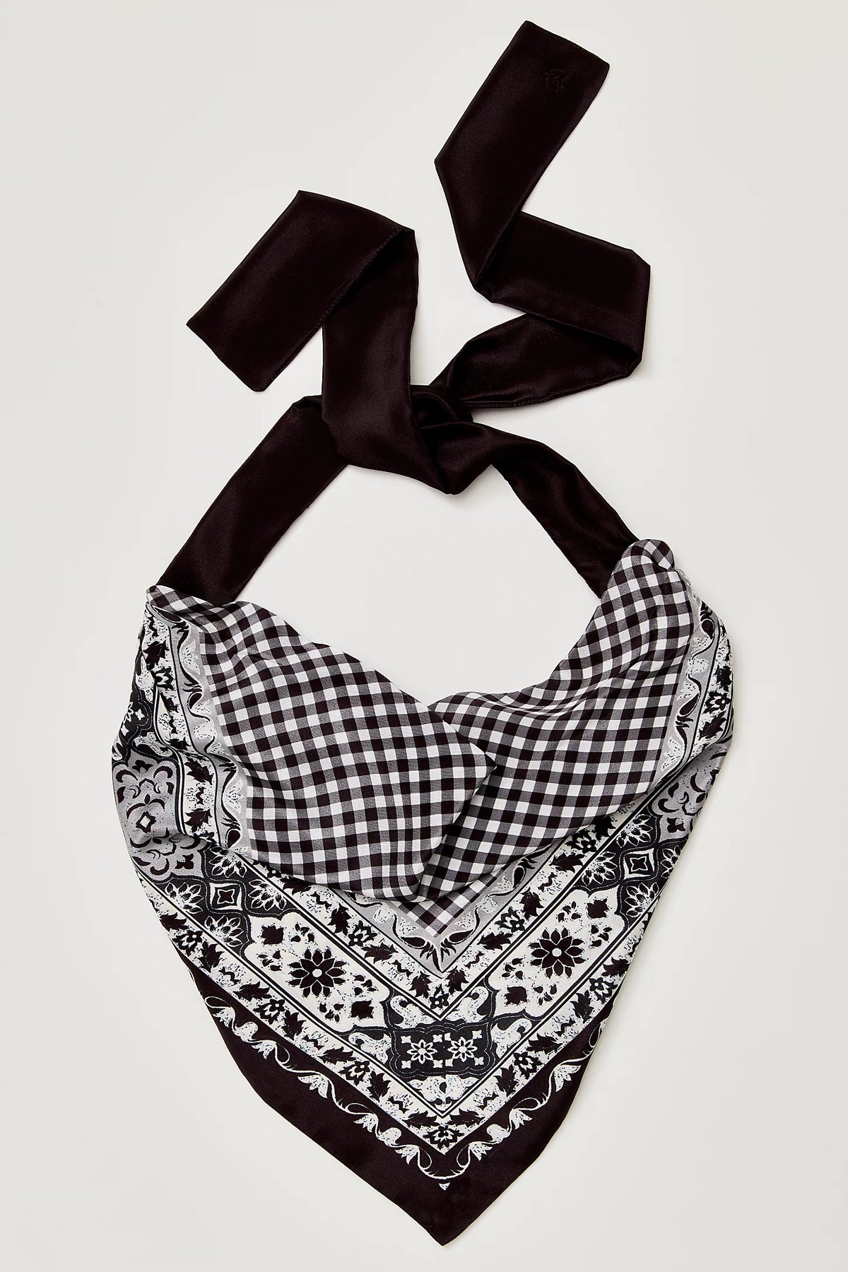 Black and white patterned bandana with a black ribbon on a light gray background