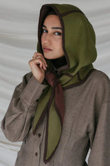 Woman wearing a green headscarf with brown accents against a plain background