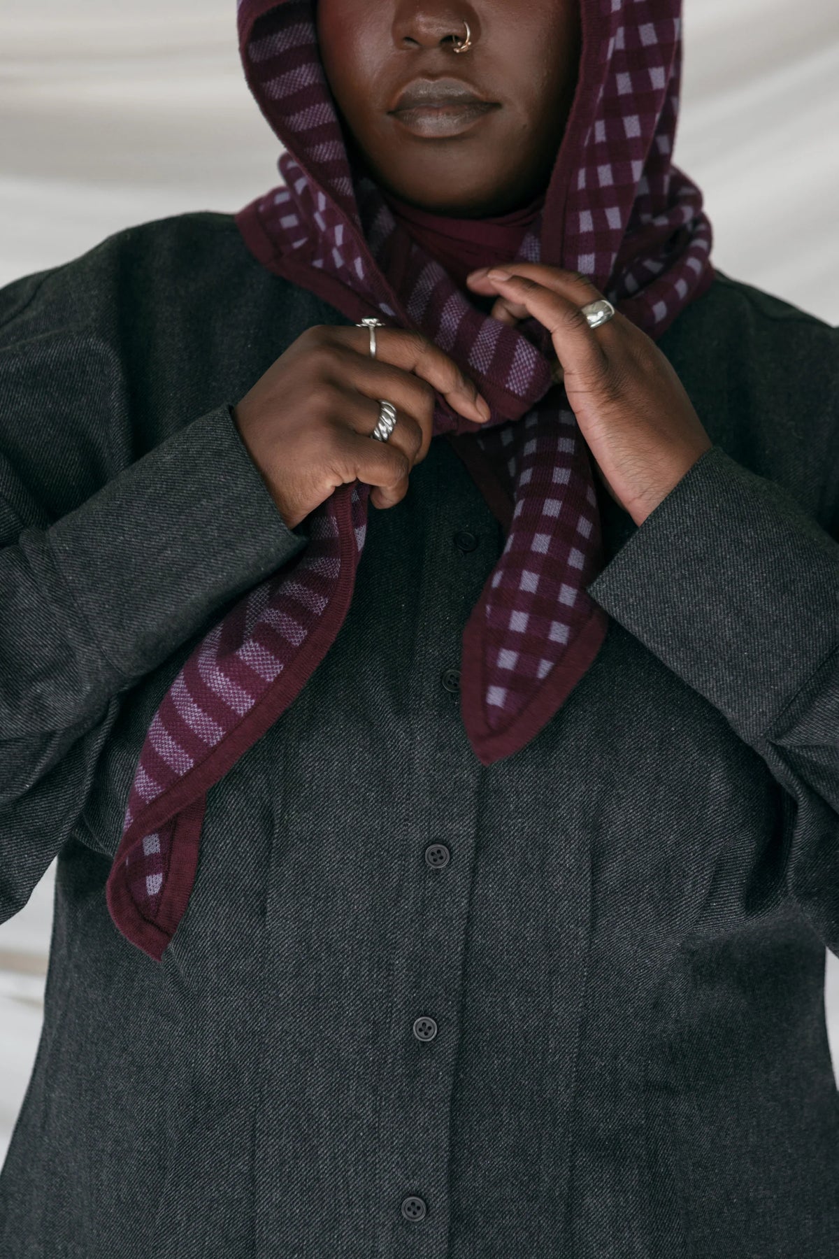 Person wearing a dark coat and a patterned scarf against a neutral background