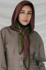 Woman wearing a brown hooded scarf against a neutral background