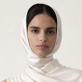 Woman wearing a white hijab and light blue top against a plain background