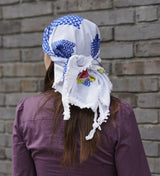 Person wearing a colorful headscarf with a brick wall background