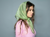Woman wearing a green headscarf against a gray background
