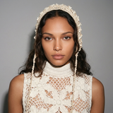 Woman wearing a white lace bonnet against a gray background